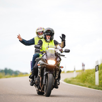 Zwei Männer auf dem Motorad winken
